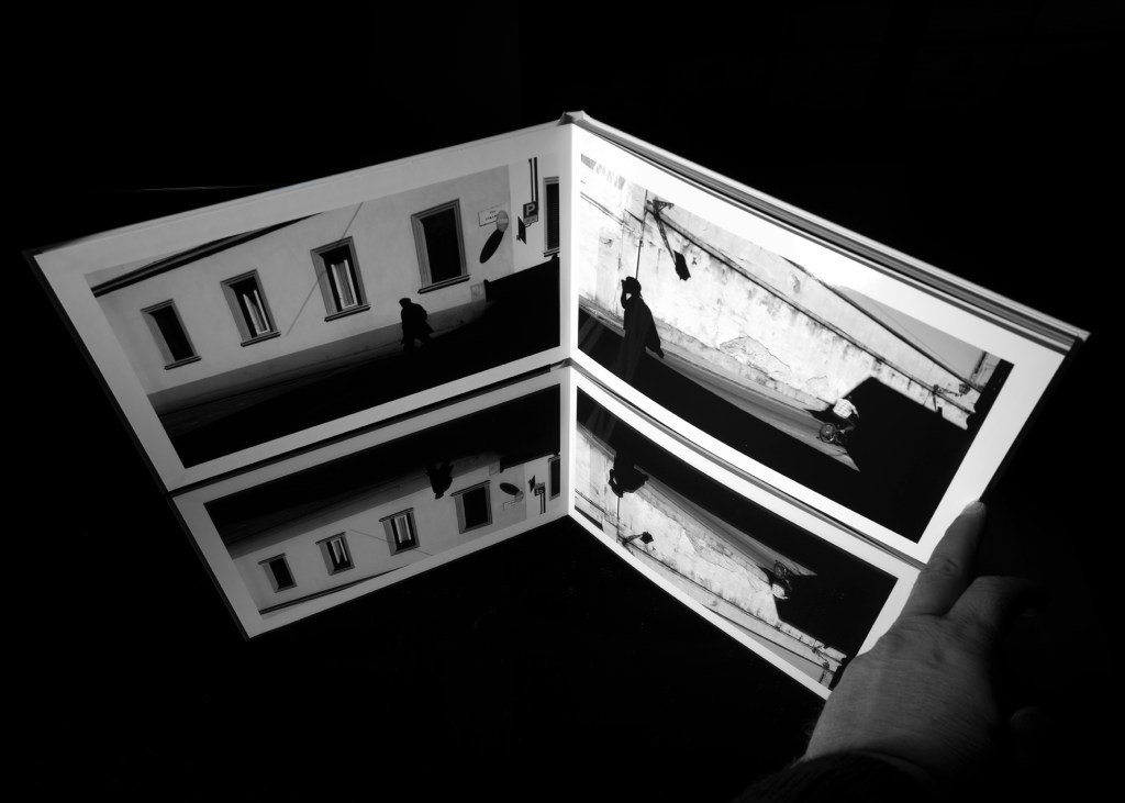 Passante ripreso dall’alto tra ombre lunghe e linee architettoniche marcate