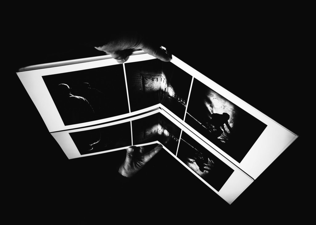 Passante immerso nelle ombre tra edifici, stile noir e forte uso dello spazio negativo