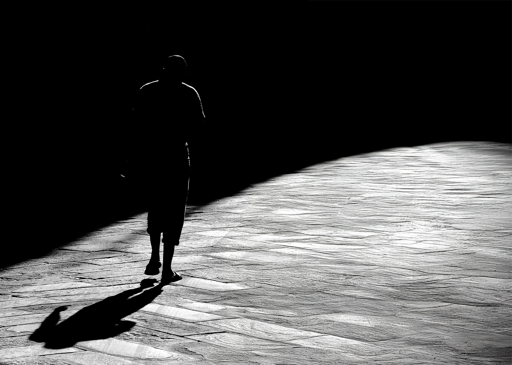 Fotografia street silhouette controluce ombra pavimento pietra luce radente minimalismo geometrico bianco nero. Street photography silhouette backlight shadow stone pavement raking light geometric minimalism black white art