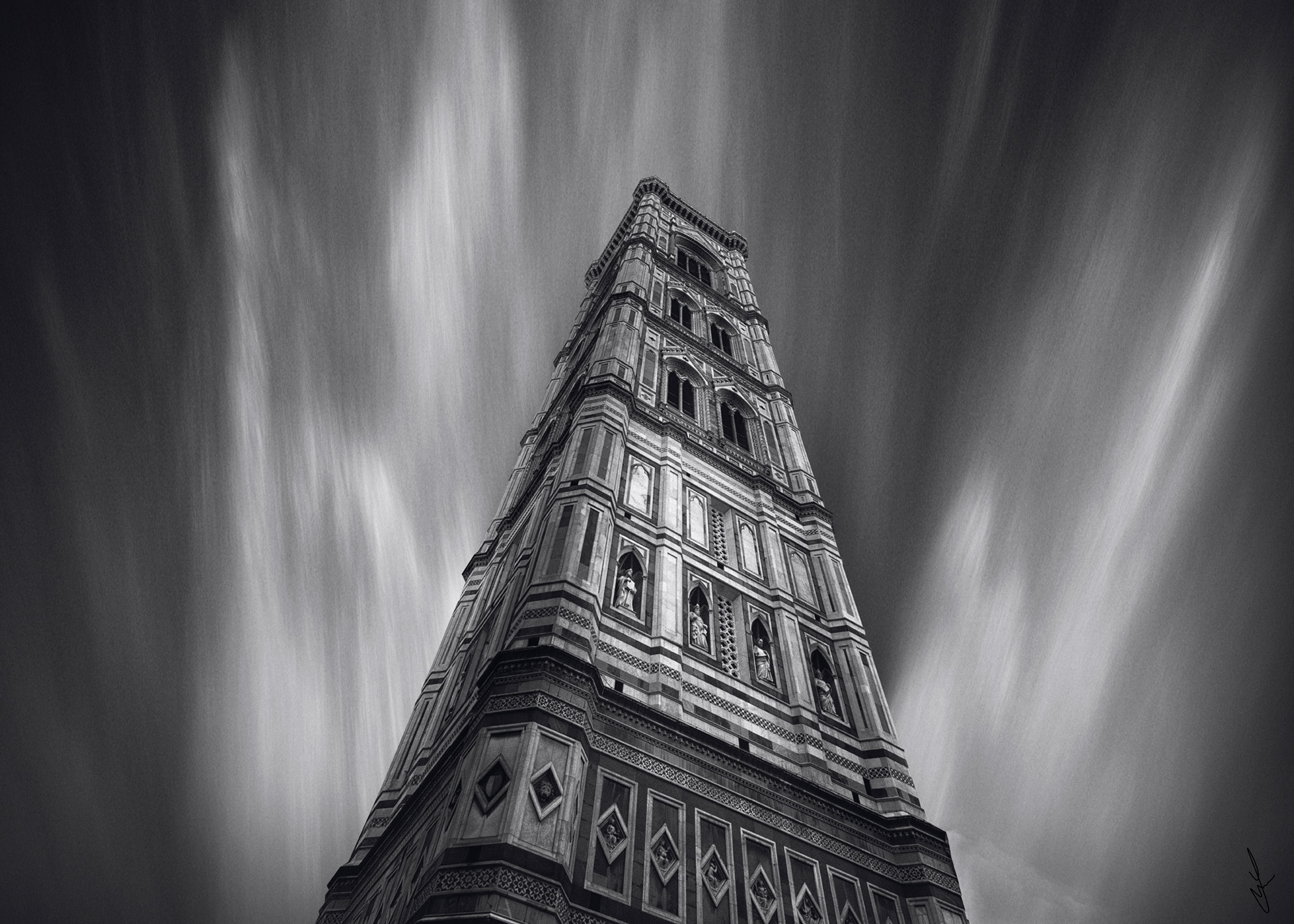 Campanile storico ripreso dal basso con linee verticali accentuate e cielo mosso Historic bell tower shot from below with emphasized vertical lines and moving sky