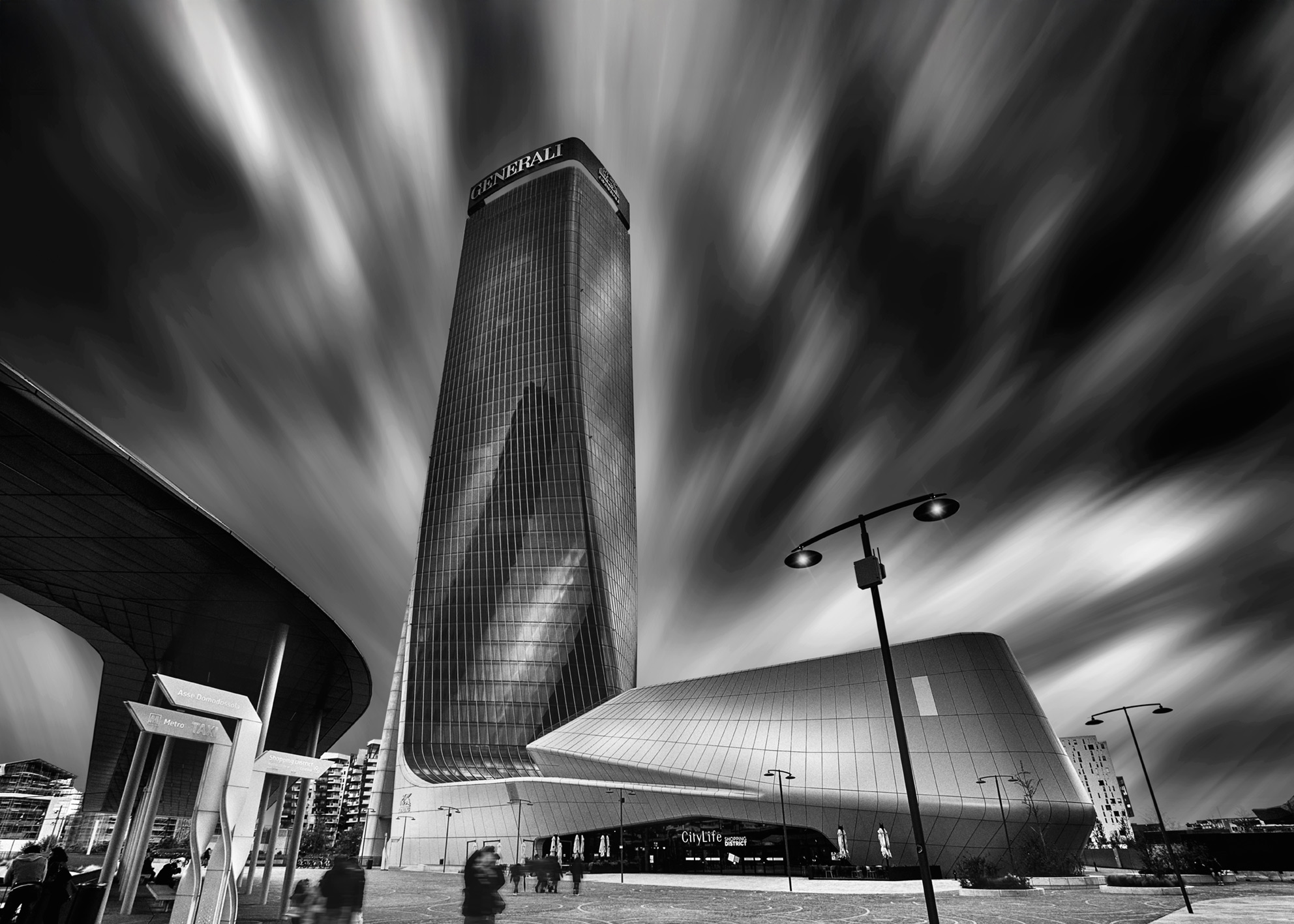 Architettura contemporanea a CityLife con torre e piazza urbana, persone in movimento e cielo dinamico a lunga esposizione Contemporary architecture in CityLife with tower and urban square, people in motion and long exposure dynamic sky